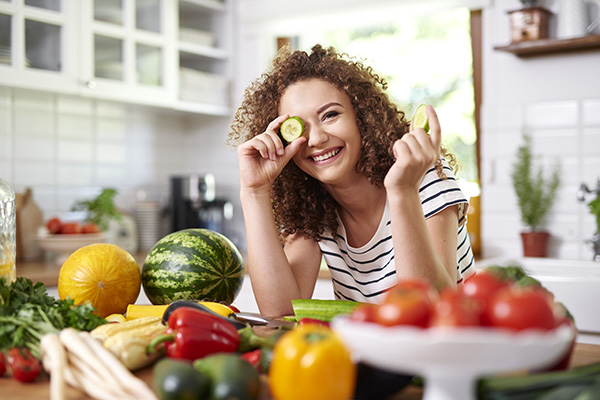 silly woman eating salad and using cucumber for eye patch