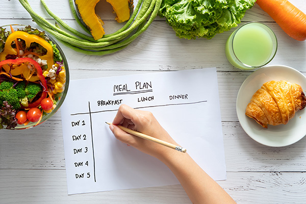 hand filling out healthy meal plan schedule
